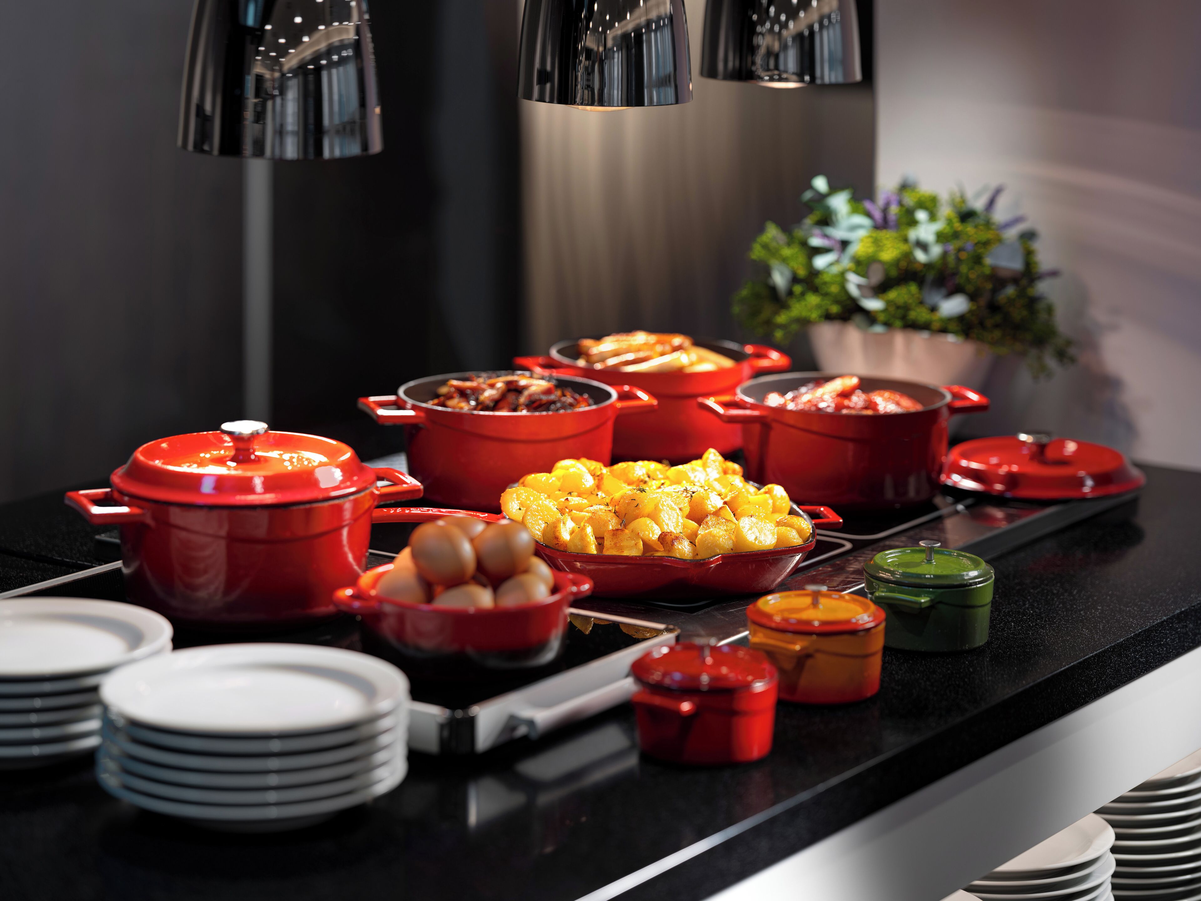 A kitchen counter with various cooking pots and pans, plates, and a potted plant.