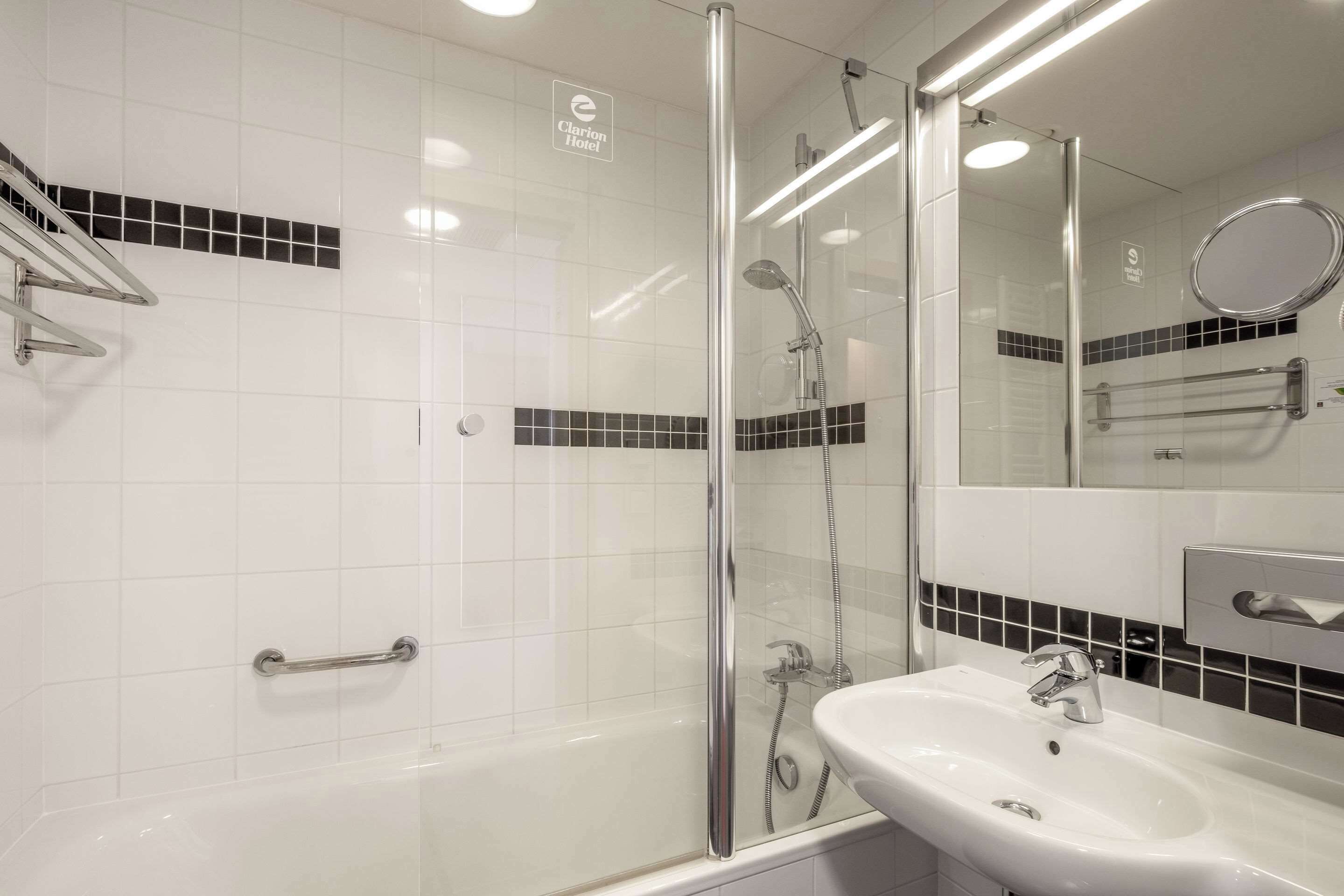 A modern bathroom with a glass-enclosed shower, a white sink, and a mirror.
