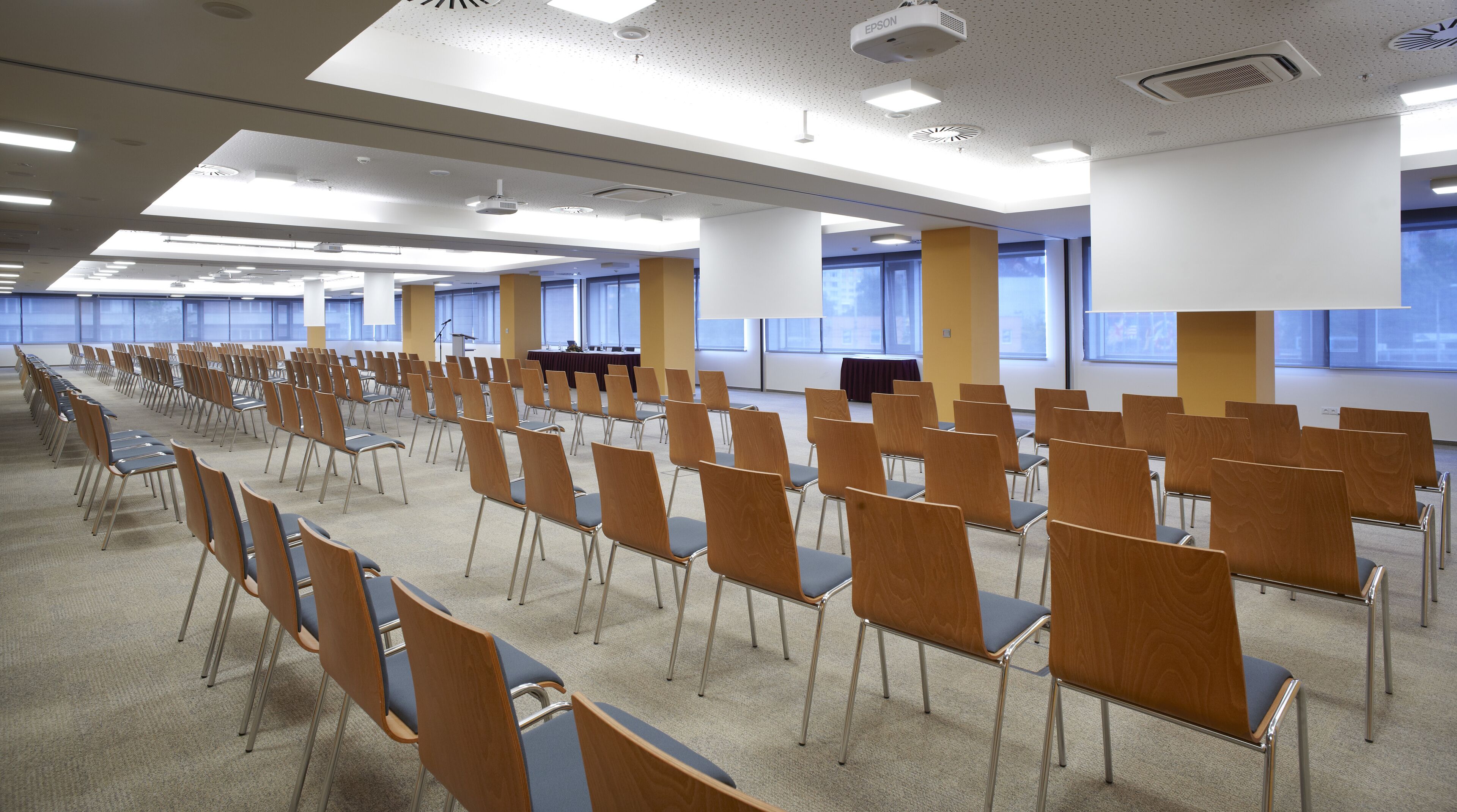A conference room with rows of chairs, a podium, and large windows.