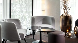 A modern living room with a round glass table, two grey sofas, a large vase with branches, and a floor lamp. - Clarion Congress Hotel Ceske Budejovice (Ceske Budejovice)