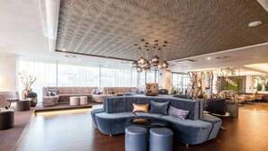 A spacious lounge with a large sectional sofa, a round coffee table, and a modern ceiling design. - Clarion Congress Hotel Ceske Budejovice (Ceske Budejovice)