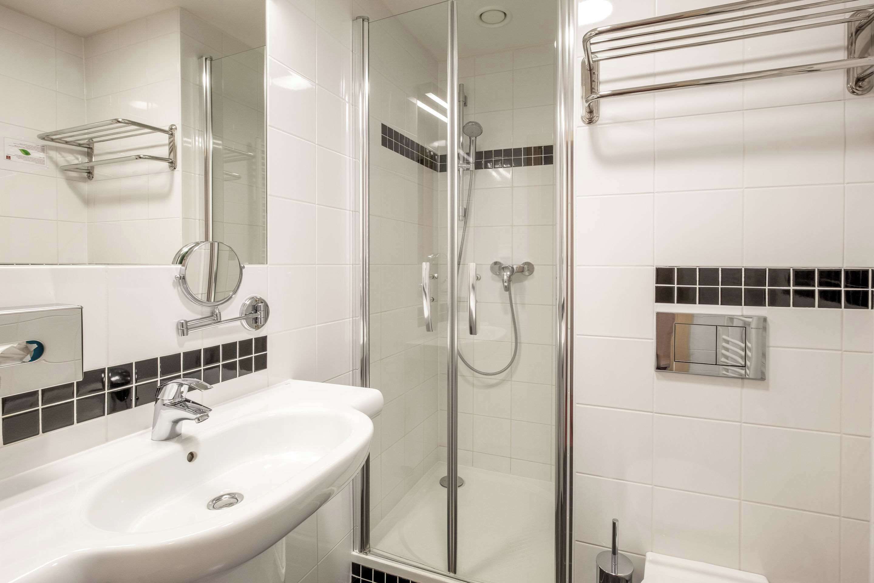 A modern bathroom with a glass-enclosed shower, a white sink, and a mirror.