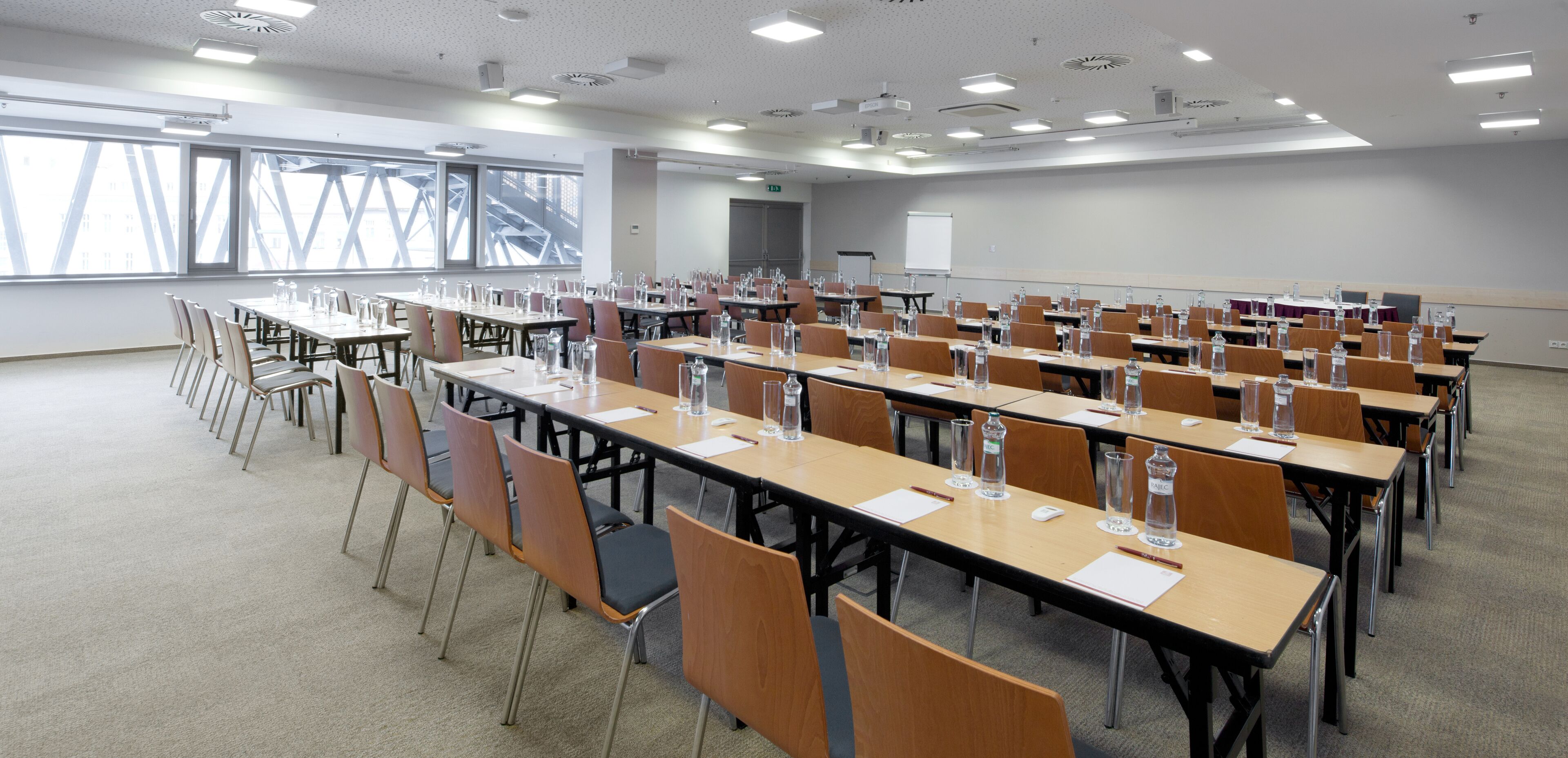 Une salle de conférence dotée de plusieurs tables et chaises, ainsi que de bouteilles d’eau et de plaques nominatives.