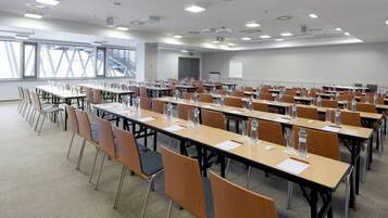 Une salle de conférence dotée de plusieurs tables et chaises, ainsi que de bouteilles d’eau et de plaques nominatives.
