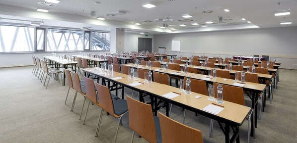 A conference room with multiple tables and chairs, equipped with water bottles and nameplates.