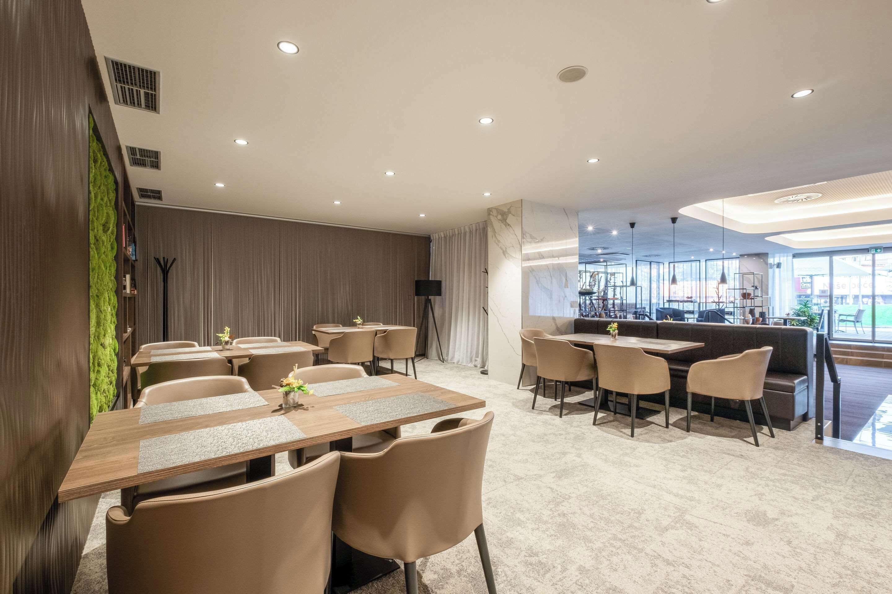 A modern hotel lobby with a seating area, a bar, and a large window providing a view of the outdoors.