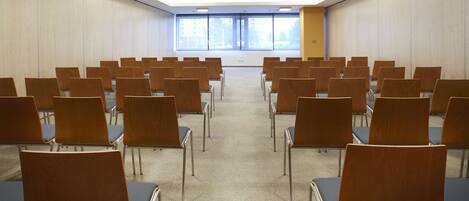A conference room with rows of chairs, a projector, and large windows.