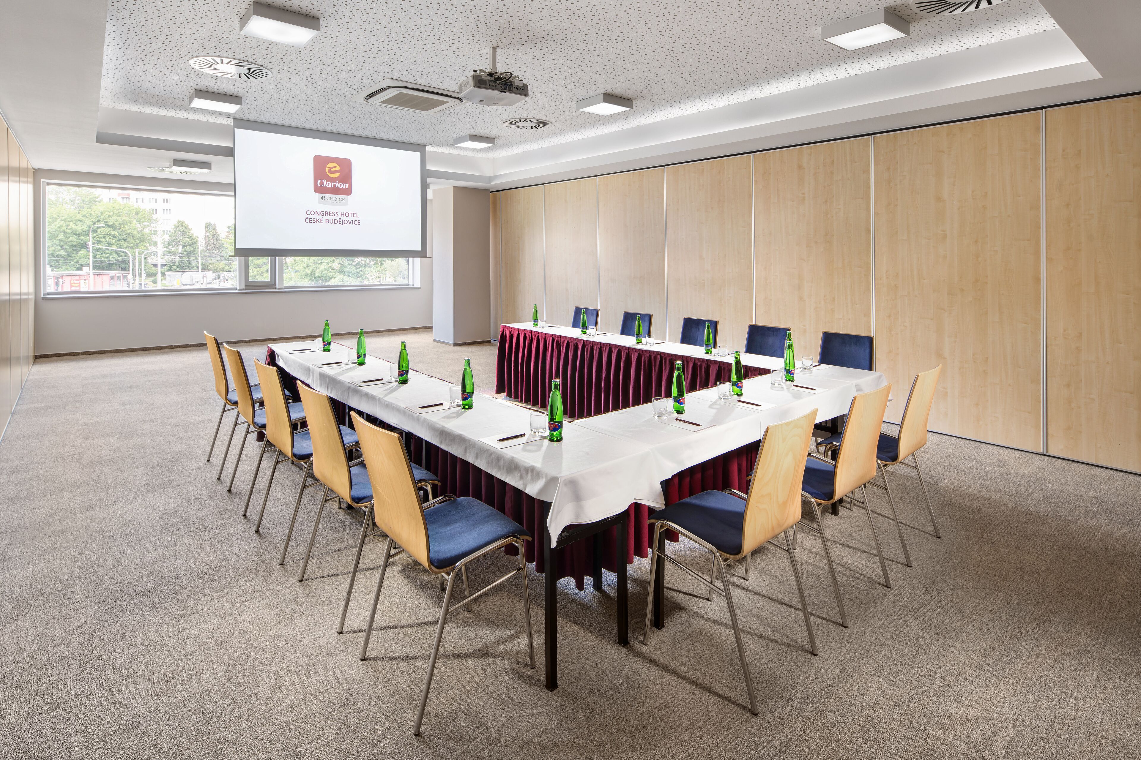 Ein Konferenzraum mit einem langen Tisch, Stühlen und einer Projektionsleinwand, die eine Präsentation zeigt.