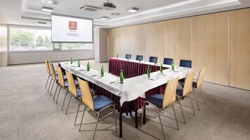 A conference room with a long table, chairs, and a projector screen displaying a presentation.