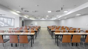 A conference room with rows of tables and chairs, equipped with water bottles and papers.