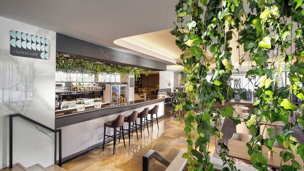 A modern bar area with a marble countertop, bar stools, and a green plant installation. - Clarion Congress Hotel Ceske Budejovice (Ceske Budejovice)