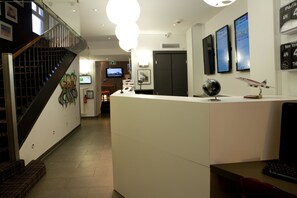 Un hall d’hôtel avec un comptoir d’accueil, un escalier et un écran de télévision.