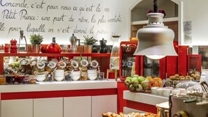 Un mostrador de l'esmorzar amb diverses menes de menjar i condiments, una paret amb una cita francesa i una màquina de cafè antiga.
