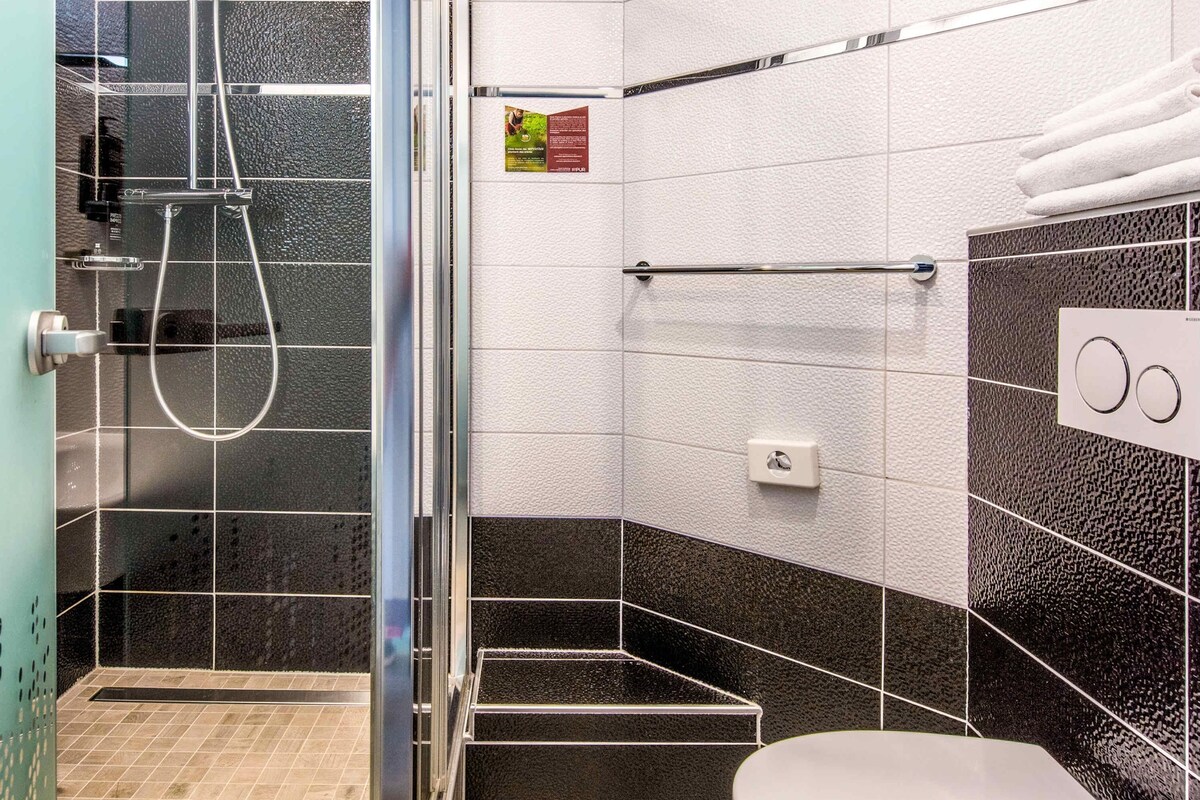 Un bagno moderno con box doccia in vetro, un water e un porta asciugamani.