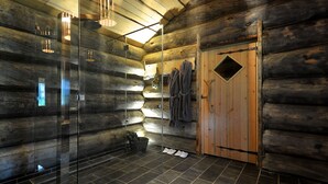 Een houten badkamer in een blokhut, met een douchecabine van glas, houten wanden en een houten deur.