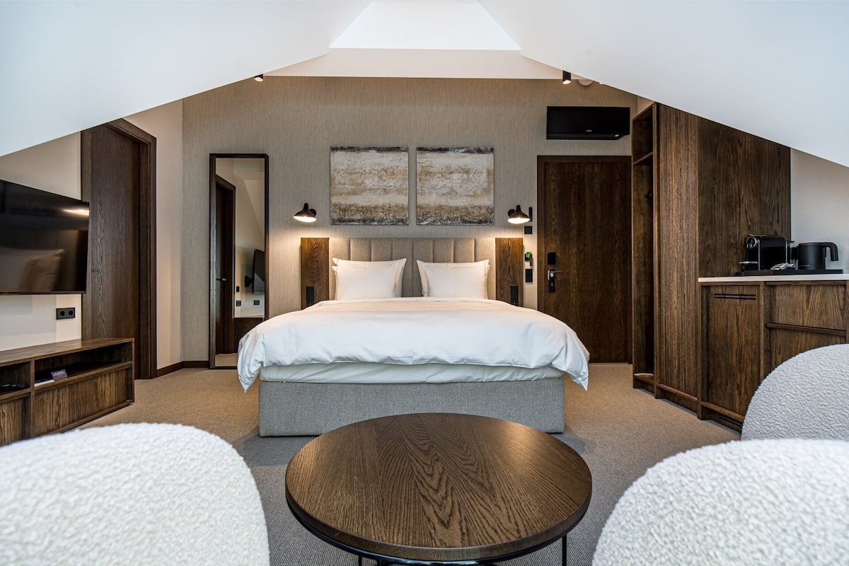 Ein modernes Hotelzimmer mit einem großen Bett, einem Flachbildfernseher, einem Essbereich und einer Küchenzeile.