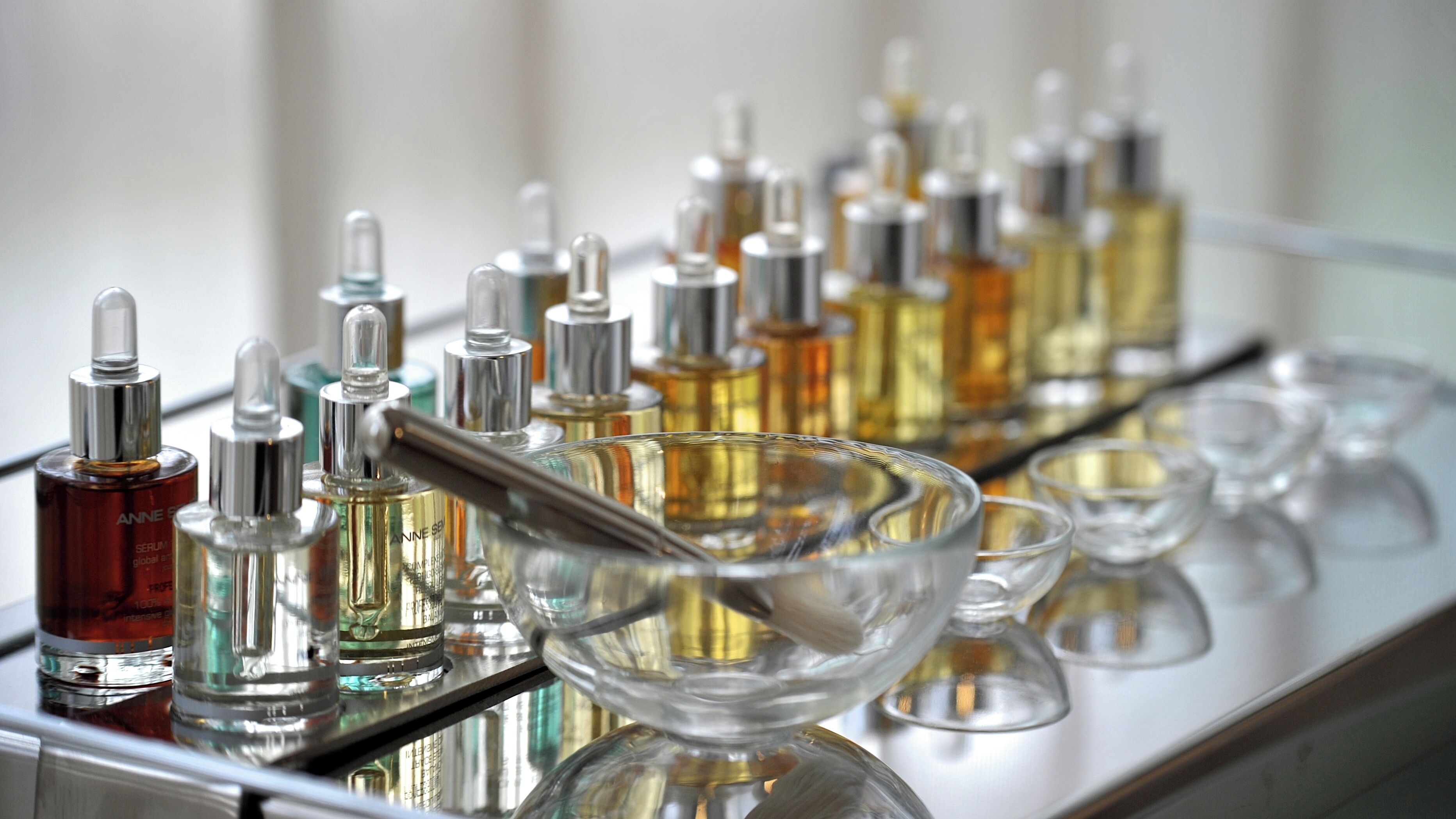 Diversos frascos de perfume sobre uma superfície espelhada.