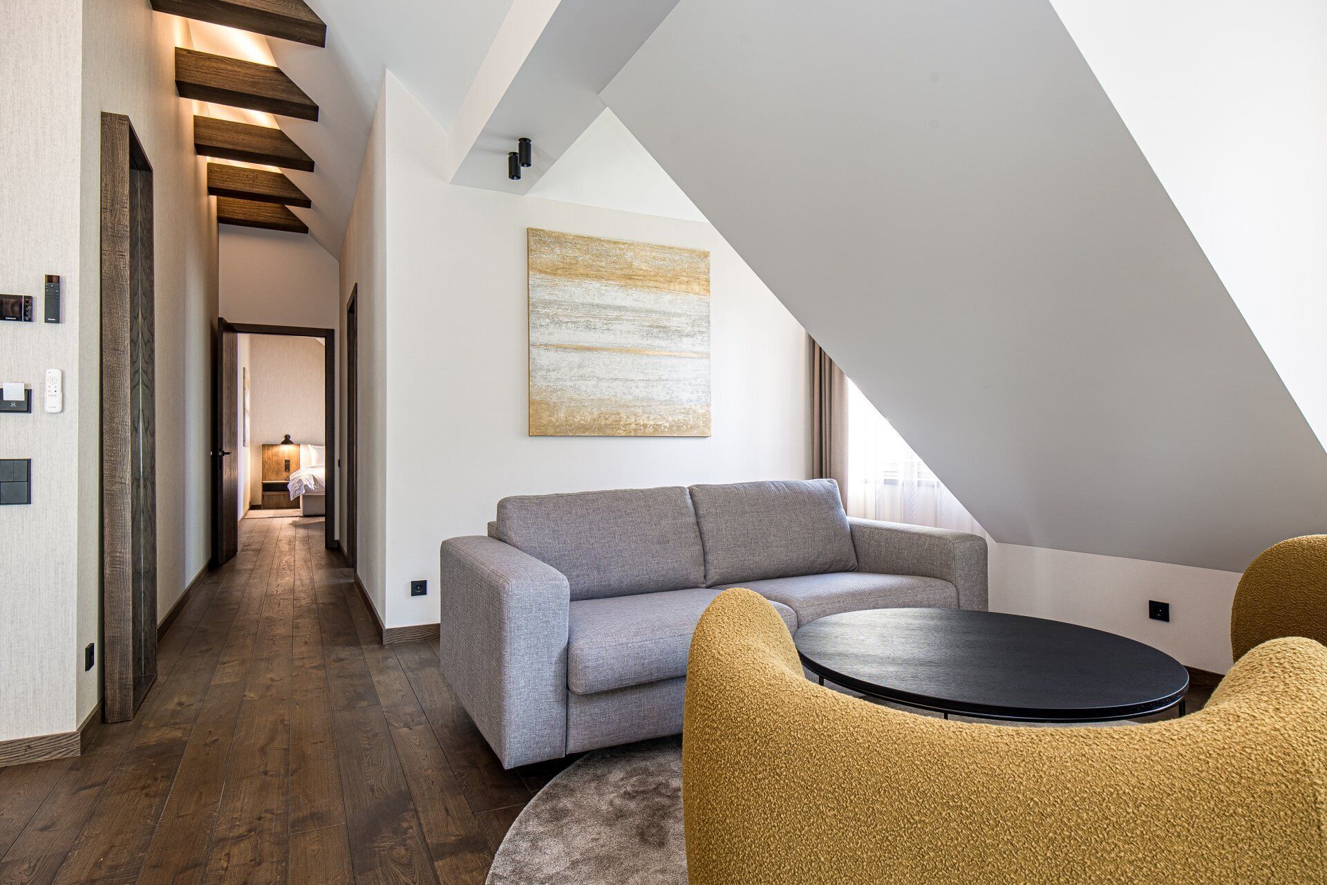 A modern loft-style room with a gray sofa, a round table, and a large window.