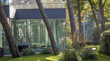 Un bâtiment moderne doté de grandes fenêtres en verre, entouré d’arbres et d’une pelouse bien entretenue.
