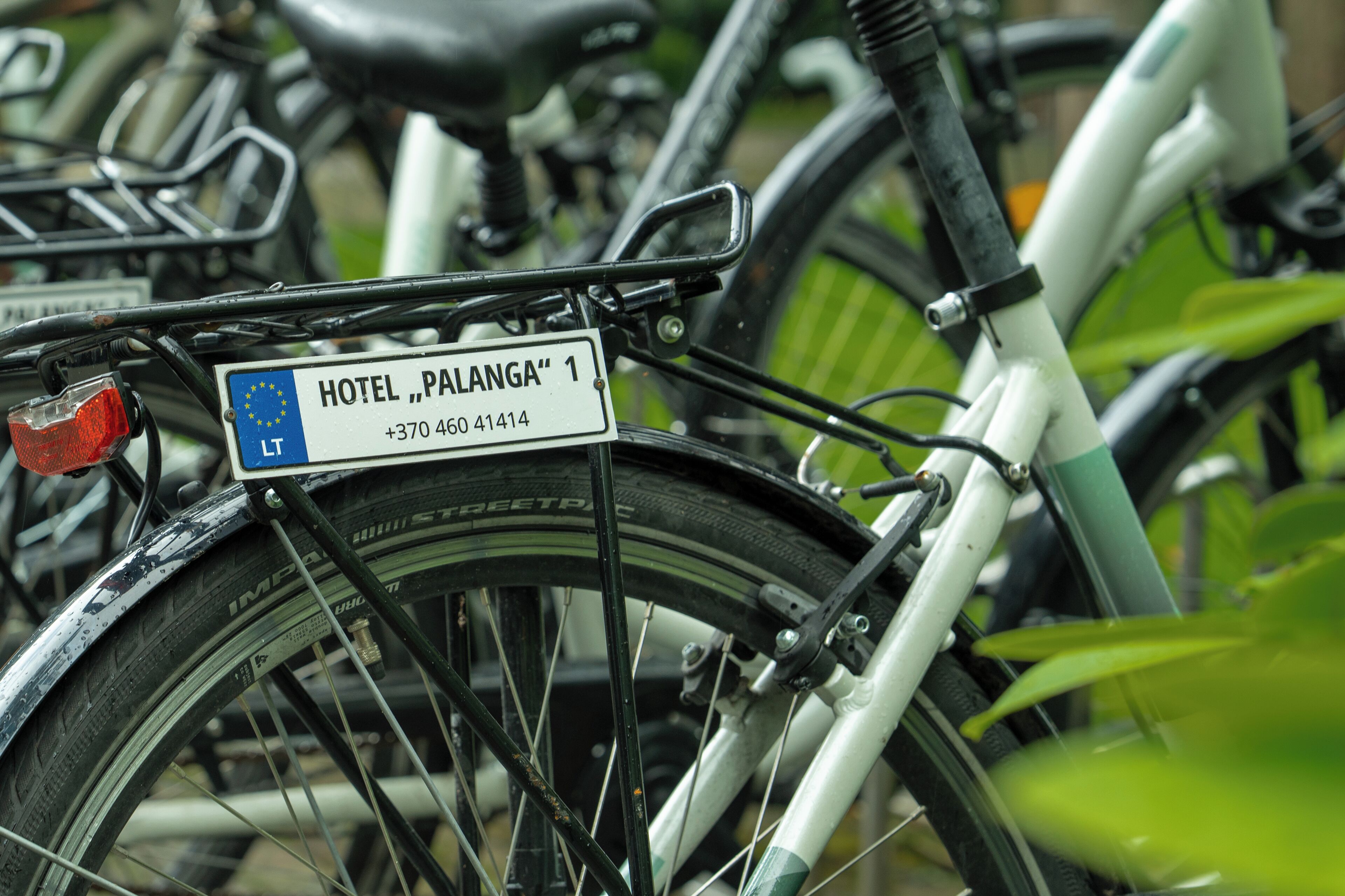 Un vélo portant une pancarte indiquant « HÔTEL PALANGA » et un numéro de téléphone.