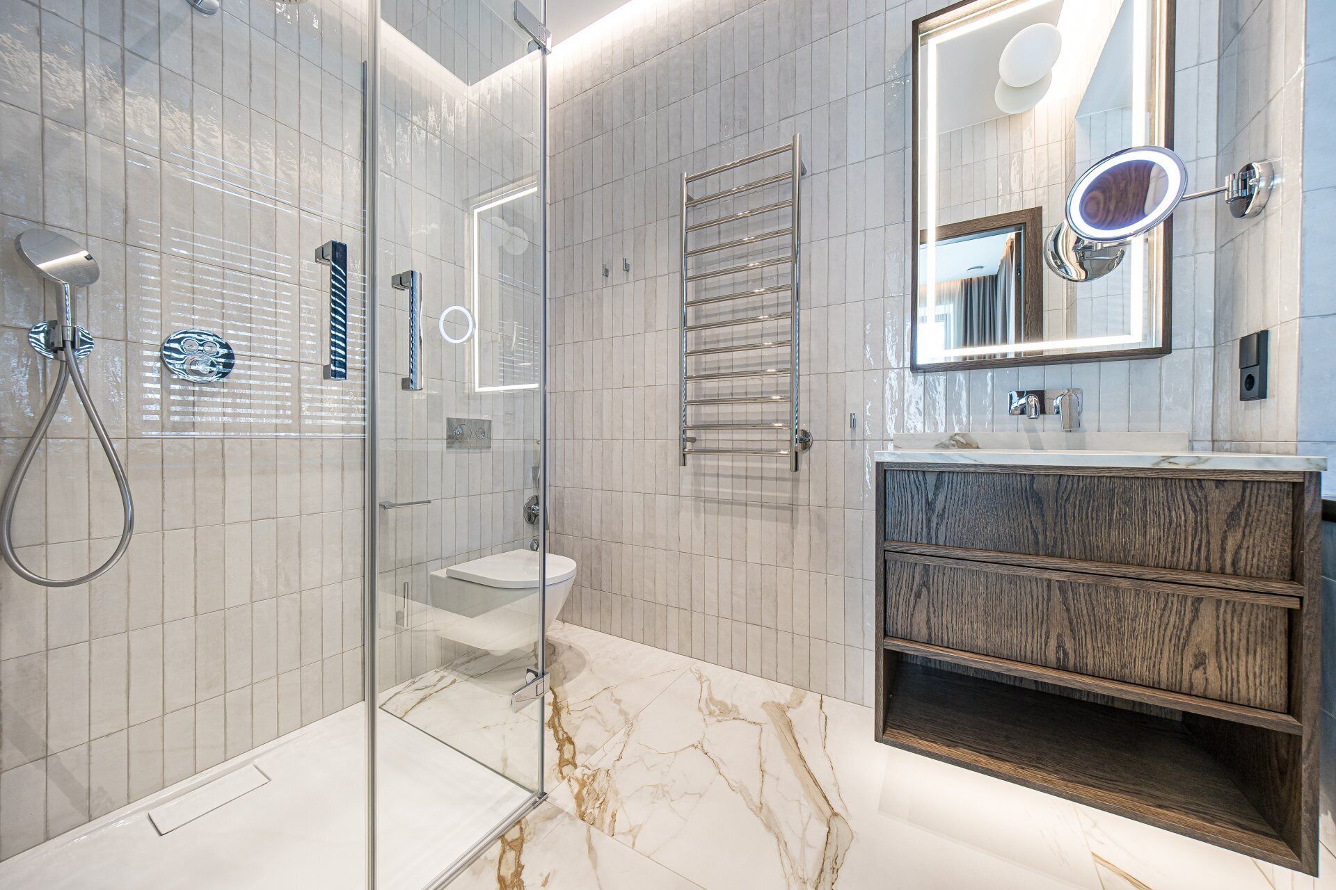 Un baño moderno con cabina de ducha de vidrio, tocador con espejo y perchero.