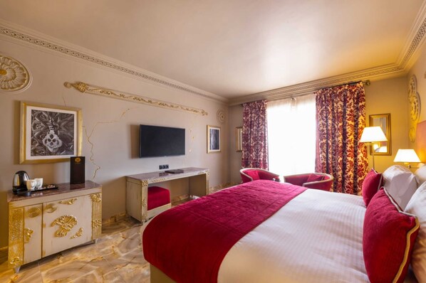 A hotel room with a large bed, a desk with a flat-screen TV, a chair, and a window with curtains. - Grand Mogador MENARA (Marrakech)
