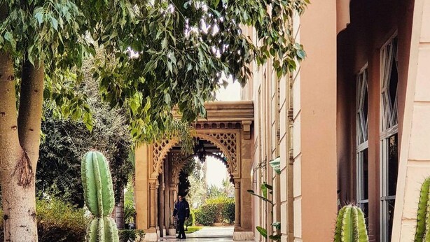 Un sendero bordeado de cactus que conduce a una entrada arqueada de un edificio.