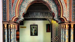 Un arco ornamentado con diseños intrincados y un cuadro enmarcado en la pared.