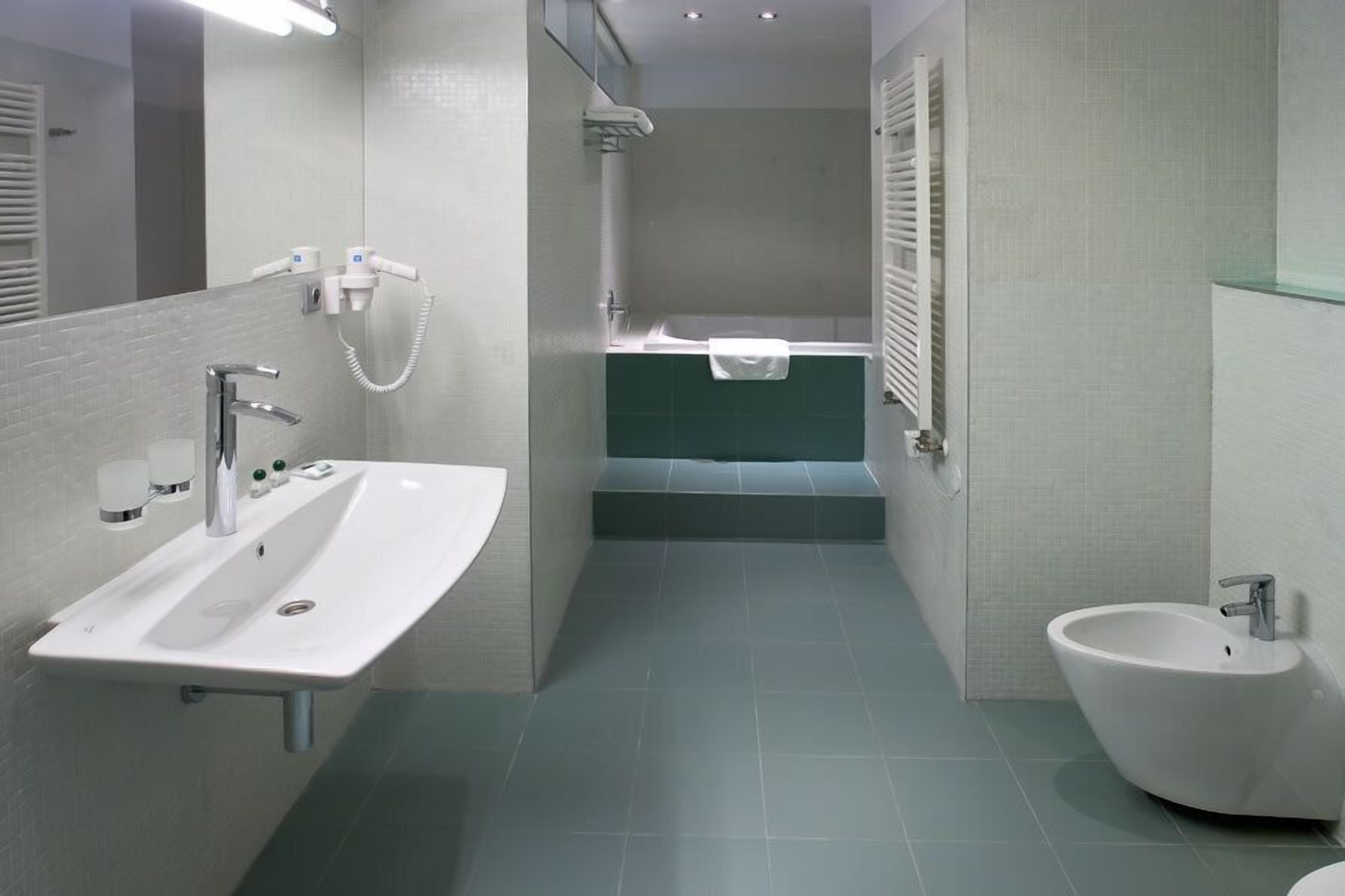Un baño moderno con un lavamanos blanco, un bidé y un espejo.