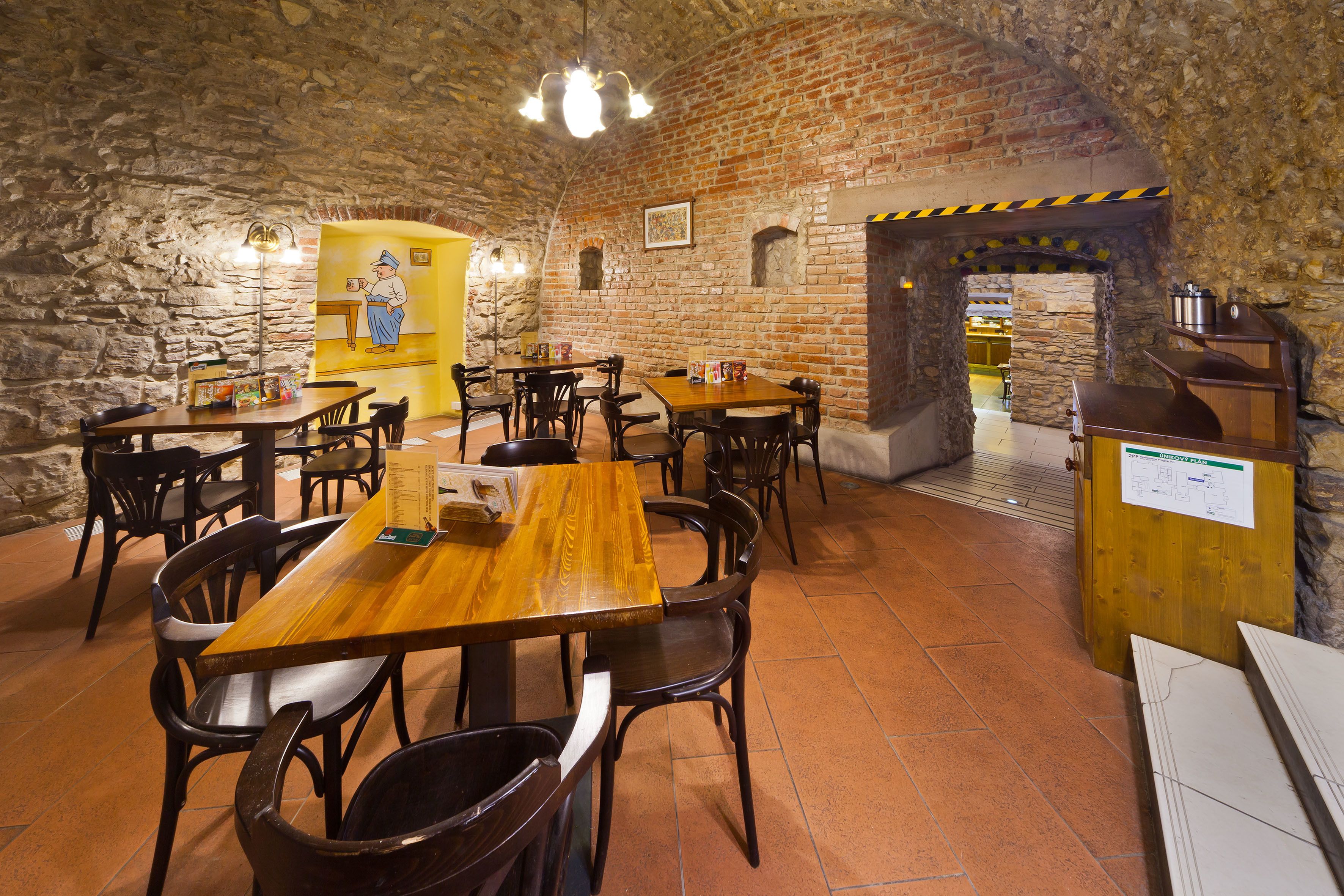 Ein Restaurant mit Steinsäulen, Holztischen und -stühlen.