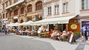 Buiten zitplaatsen bij een restaurant aan een geplaveide straat.