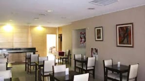 A dining area with tables and chairs, a counter, and artwork on the walls. - Argentina Tango Hotel (Buenos Aires)
