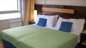 A hotel room with a bed, a nightstand, a lamp, and a window with curtains. - Argentina Tango Hotel (Buenos Aires)