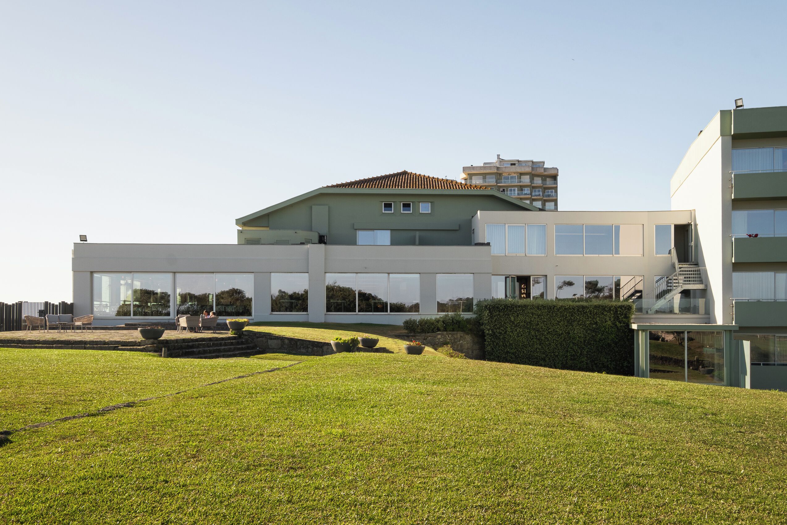 A modern building with large windows, a flat roof, and a well-maintained lawn.
