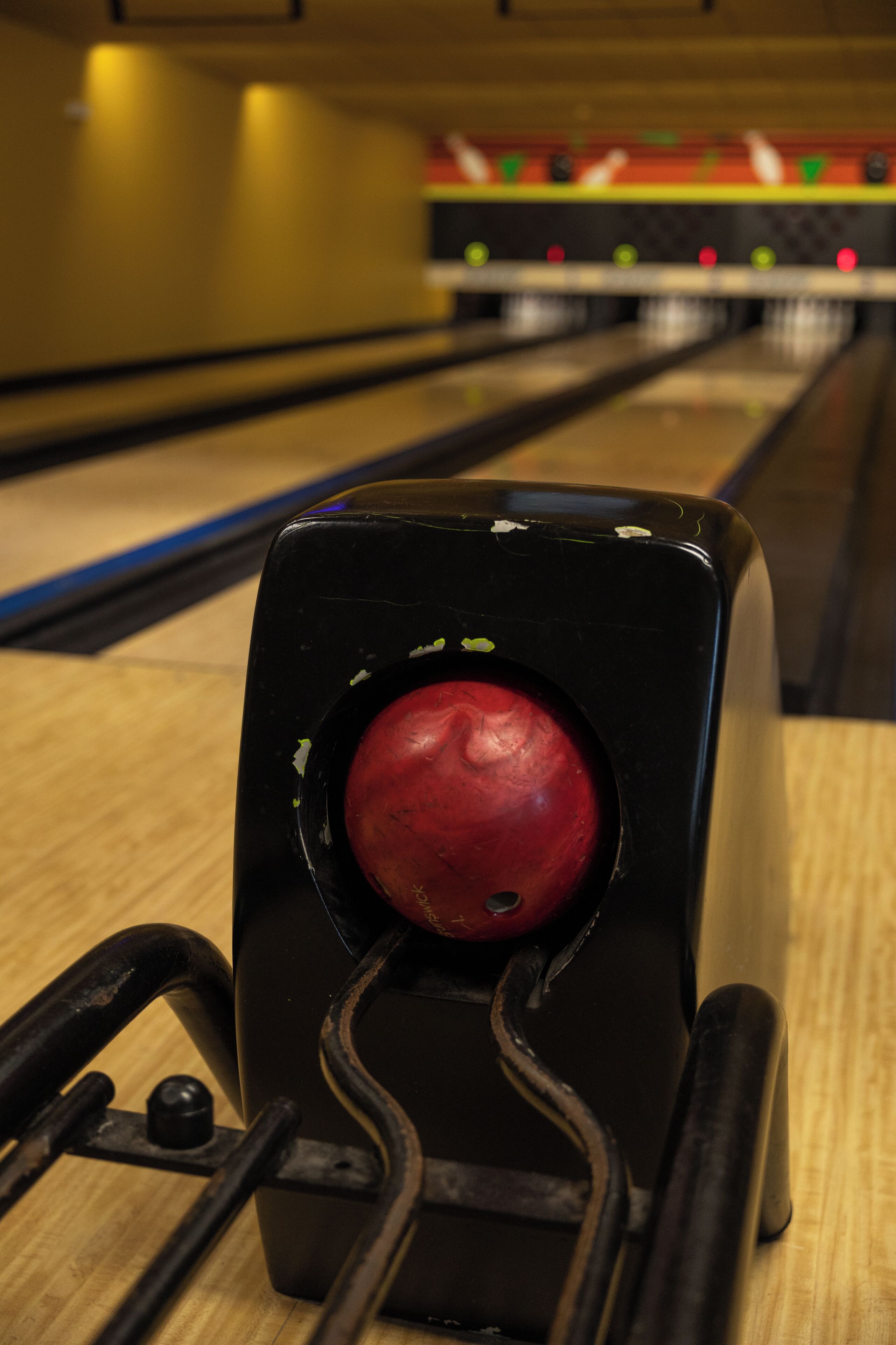 Una bolera con un primer plano de una bola de bolos en una máquina lanzadora de bolos.