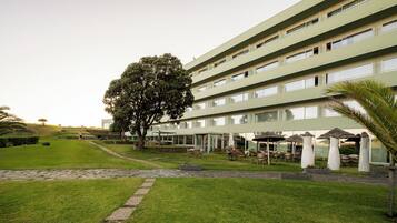A hotel with a modern design, featuring a large tree and outdoor seating area.