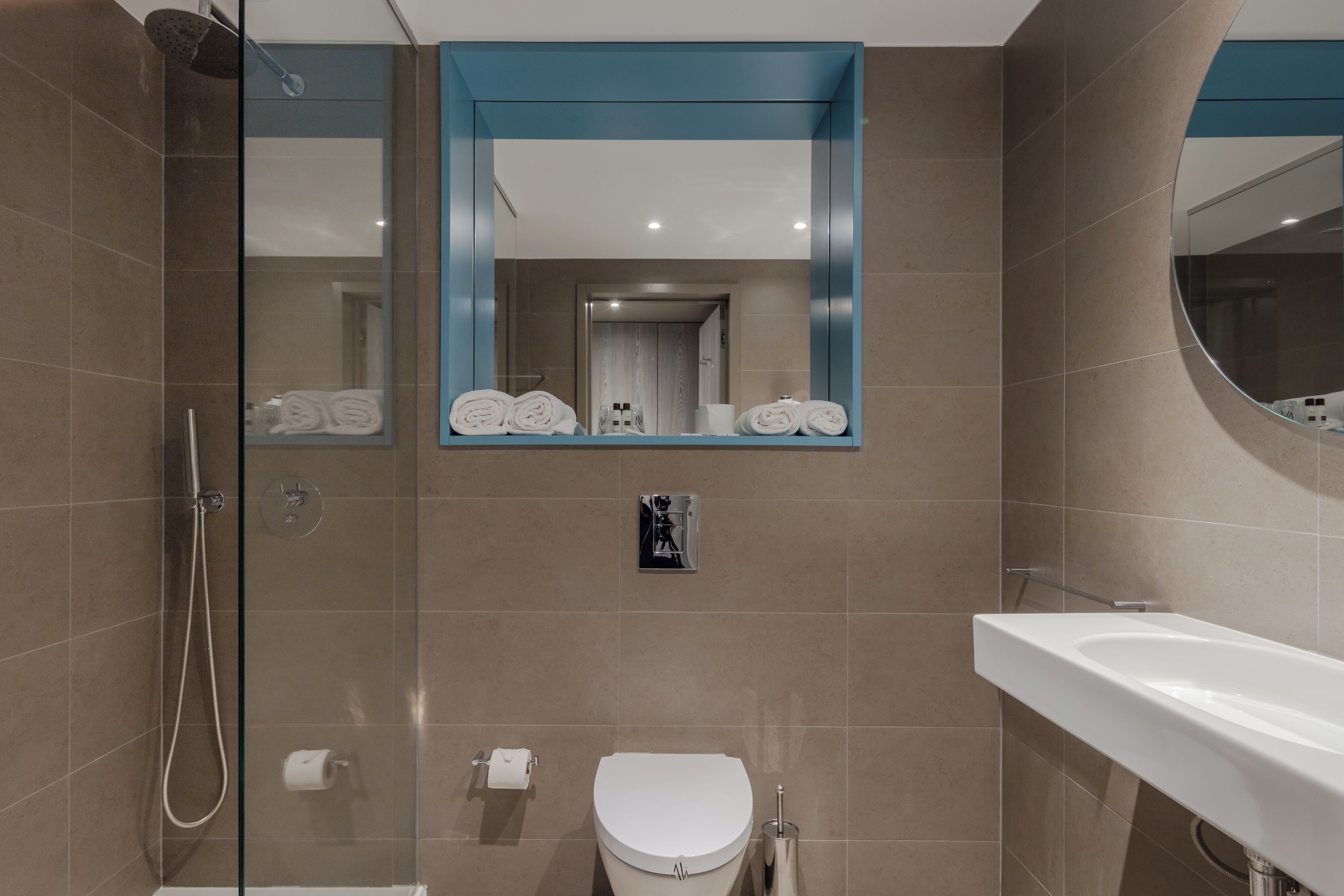 A modern bathroom with a glass shower enclosure, a toilet, and a sink.