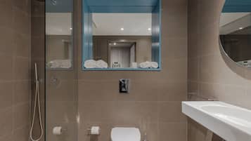 Un baño moderno con cabina de ducha de vidrio, inodoro y lavabo.