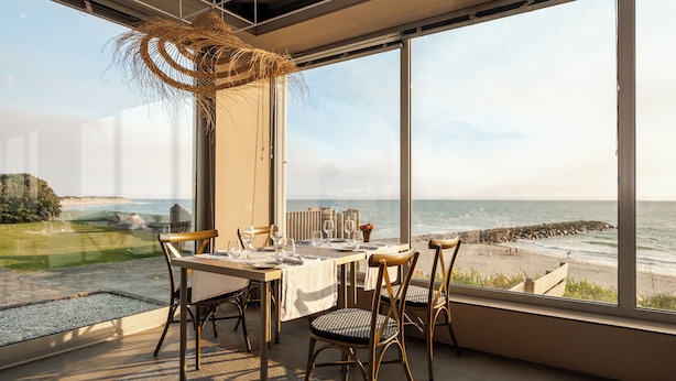 A dining area with a table set for four, overlooking a beach. - Axis Ofir Beach Resort Hotel (Esposende)