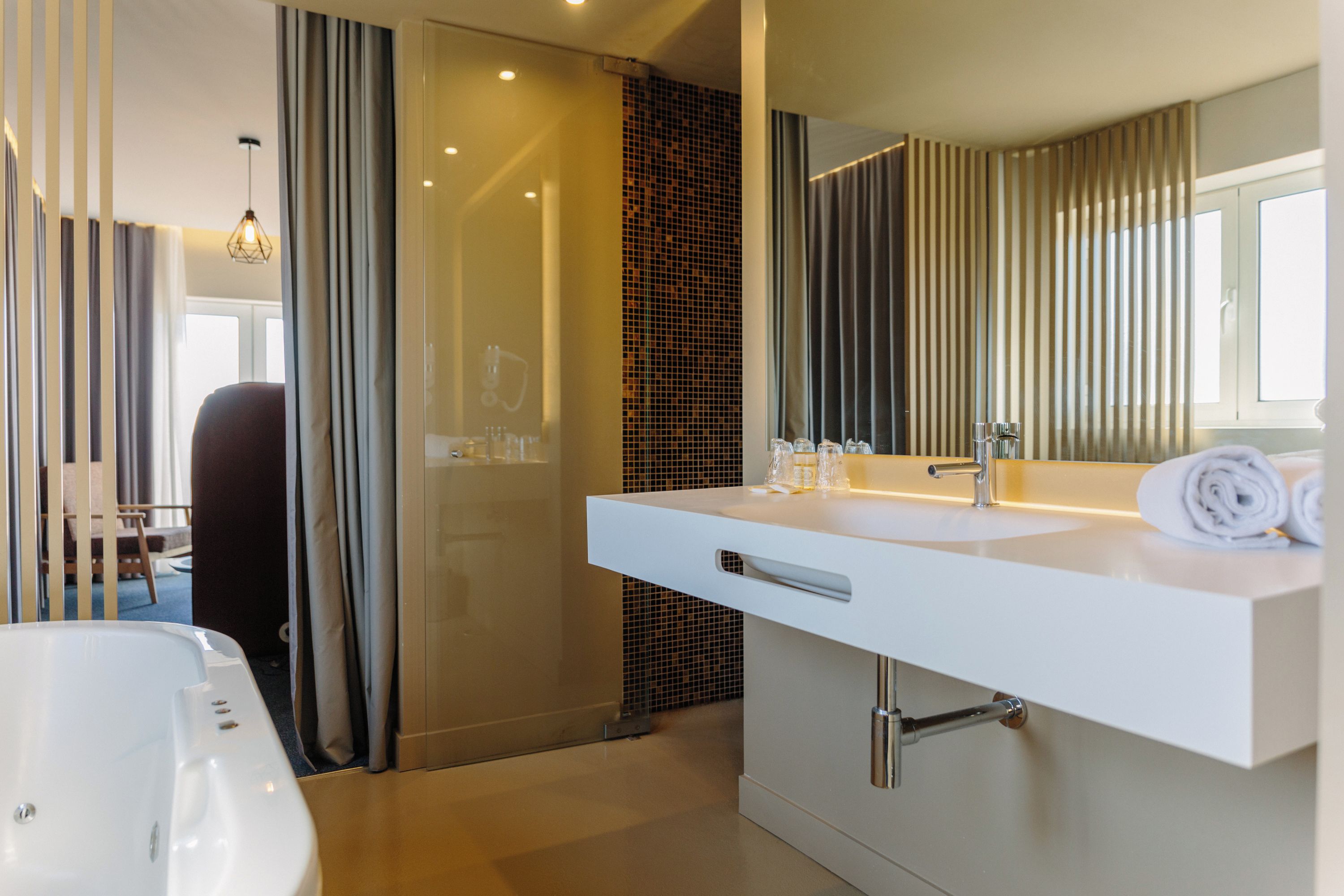 Une salle de bain moderne avec un grand miroir, un lavabo blanc et une baignoire.