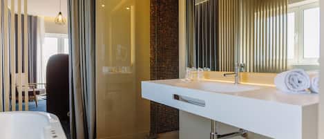 Un baño moderno con un espejo grande, un lavamanos blanco y una bañera.