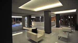 A modern lobby with a reception desk, seating area, and a large ceiling light fixture. - Axis Ofir Beach Resort Hotel (Esposende)