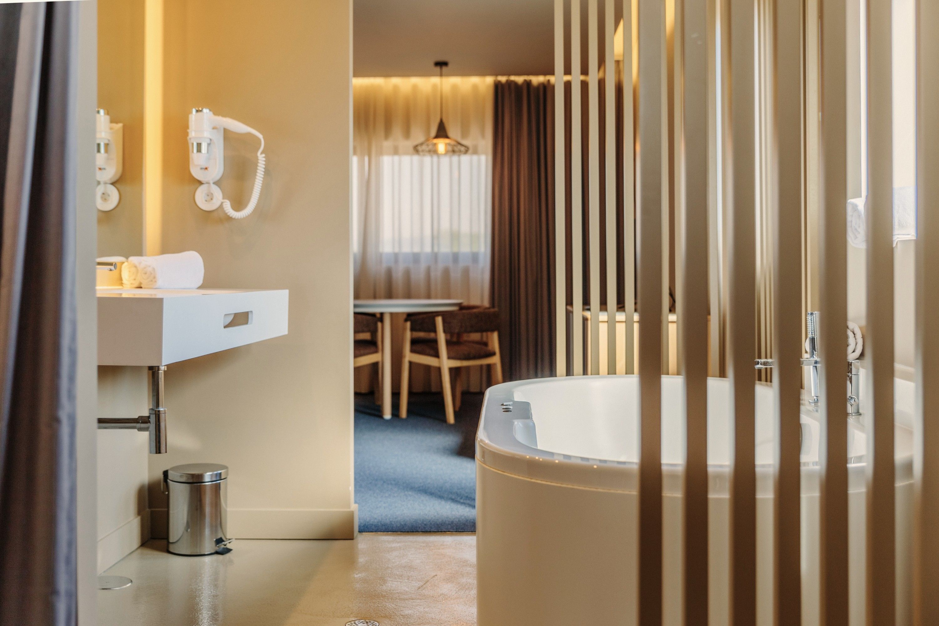 Un baño moderno con una bañera grande, un lavabo y un inodoro. Hay un espejo sobre el lavabo y un tendedero con toallas.