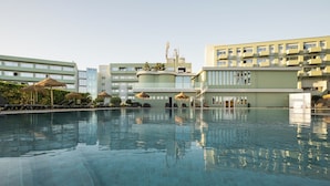 A swimming pool with lounge chairs and umbrellas, surrounded by buildings with balconies and a clear sky. - Axis Ofir Beach Resort Hotel (Esposende)