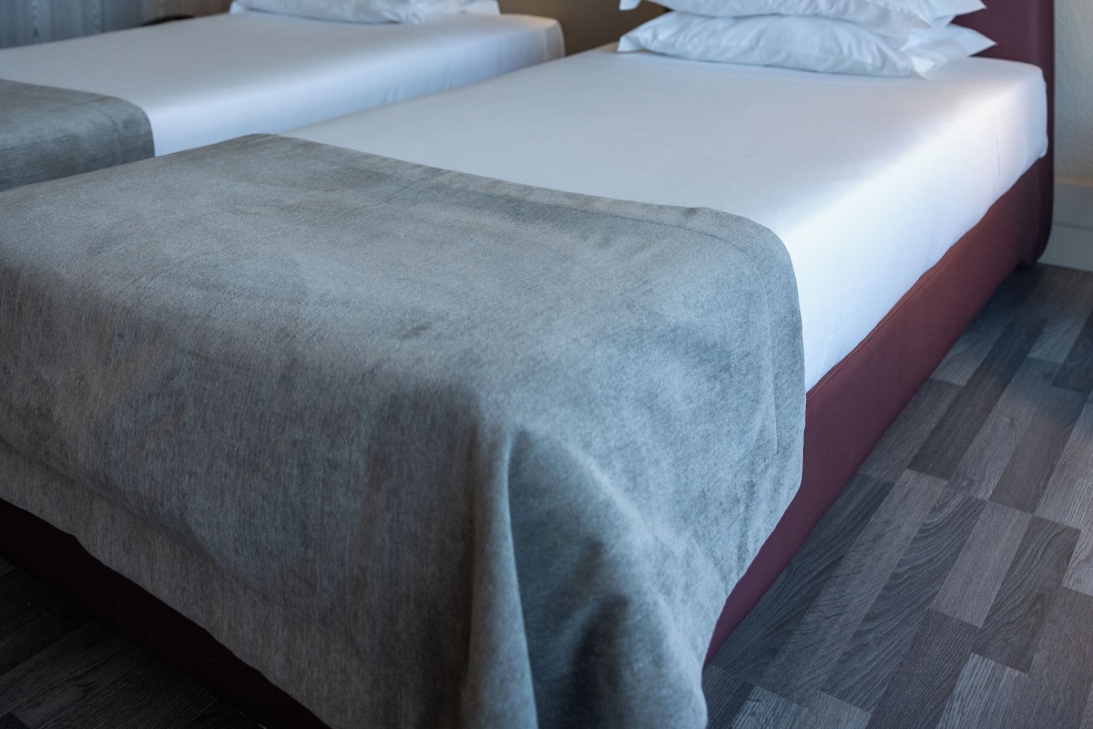 Una habitación de hotel con dos camas, un espejo grande y un diseño moderno en la pared.