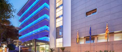 Een modern hotel met een meerlaags gebouw, een glazen gevel en een goed verlichte ingang.