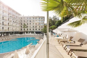 Un hôtel doté d’une grande piscine, de chaises longues et d’un immeuble à plusieurs étages avec des balcons.