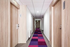 Un couloir d’hôtel aux murs lambrissés, doté d’un tapis à carreaux et d’une enseigne indiquant le numéro de chambre 531.