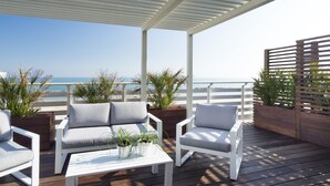 A wooden deck with white furniture, including two sofas and a coffee table, surrounded by potted plants. - Hotel LaMorosa (Rimini)