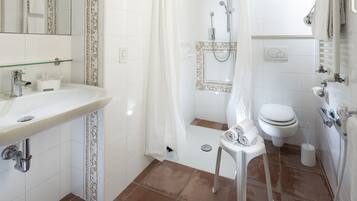 Un baño con lavamanos, inodoro, ducha y un perchero para toallas.